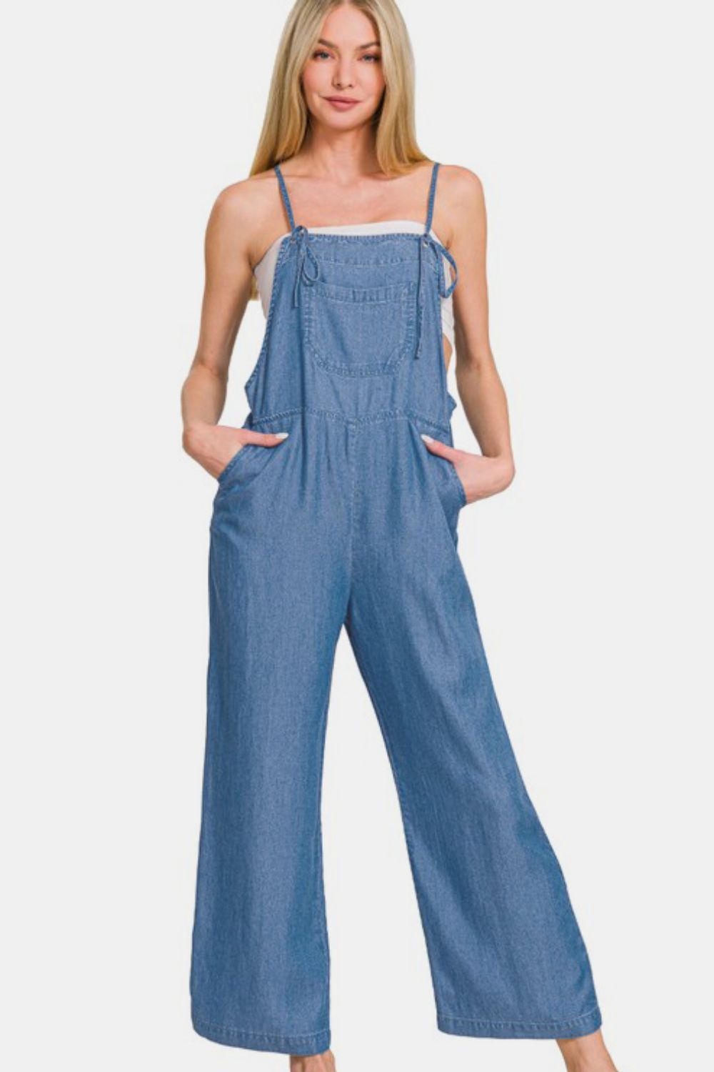 Woman in washed adjustable strap wide leg denim overalls, showcasing a trendy and casual laid-back style.