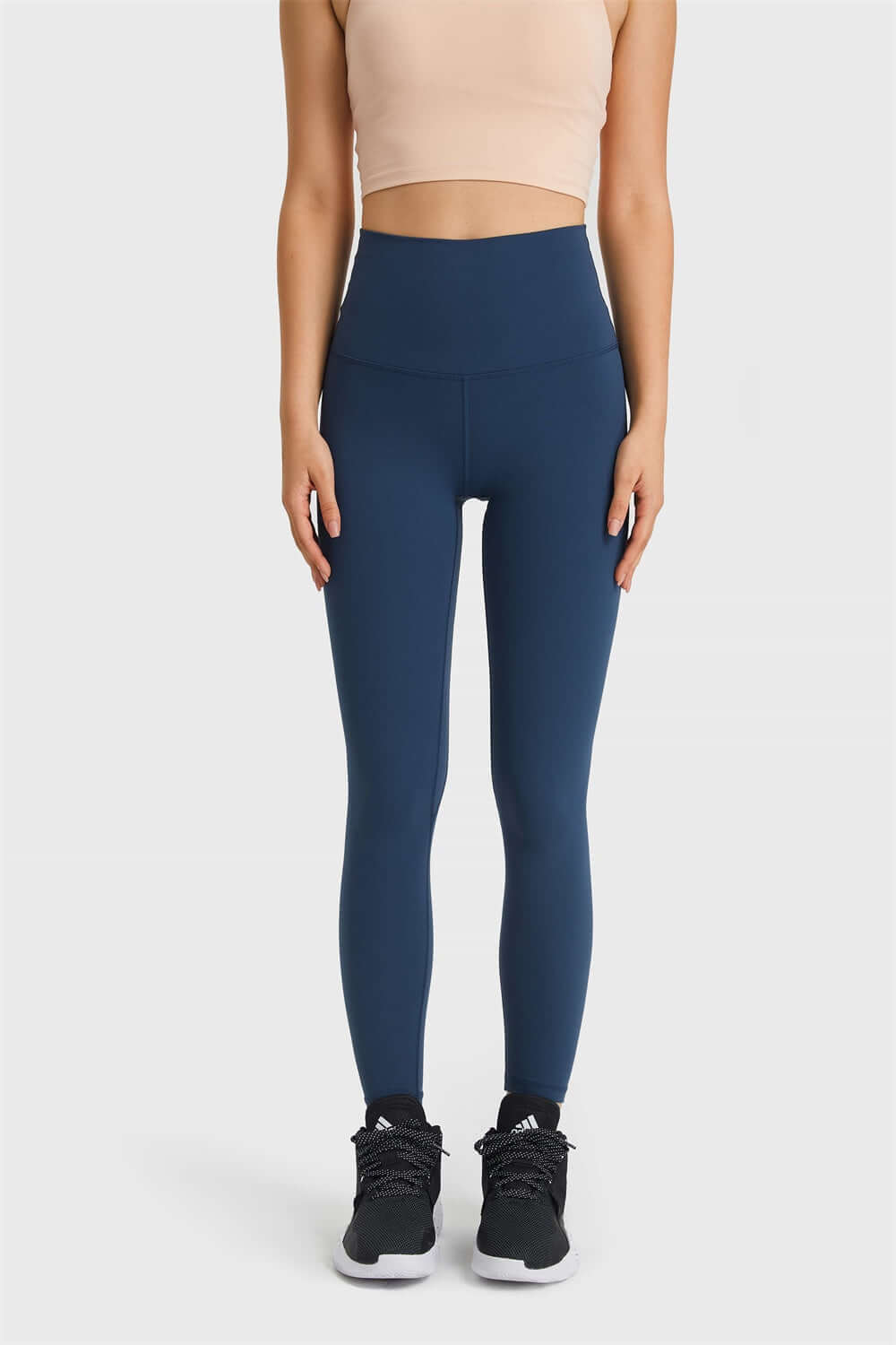 Model wearing Millennia Ultra Soft High Waist Leggings in blue, showcasing a sleek athleisure look with a crop top and sneakers.