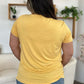 Woman wearing a yellow Bamboo V-Neck High-Low T-Shirt with slightly stretchy fabric, rear view showcasing casual fit and soft material