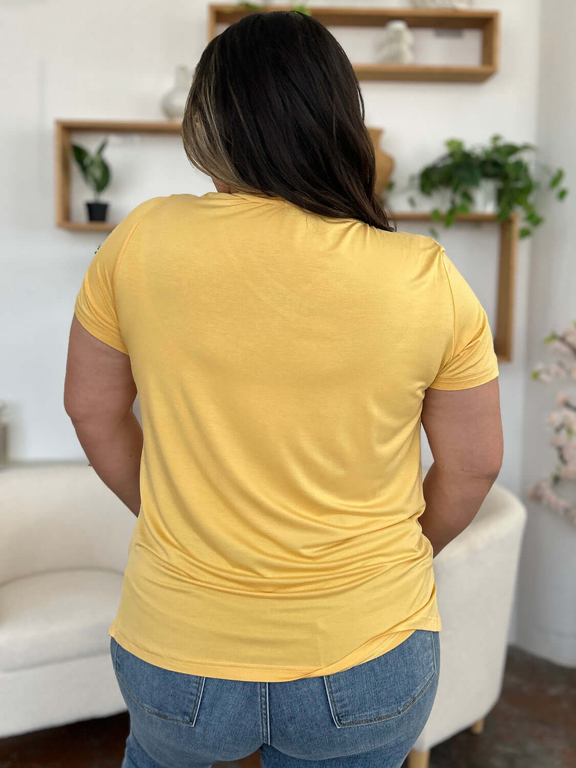 Woman wearing a yellow Bamboo V-Neck High-Low T-Shirt with slightly stretchy fabric, rear view showcasing casual fit and soft material