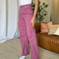 Woman wearing pink high rise wide leg jeans with white tank top and sneakers in a stylish indoor setting