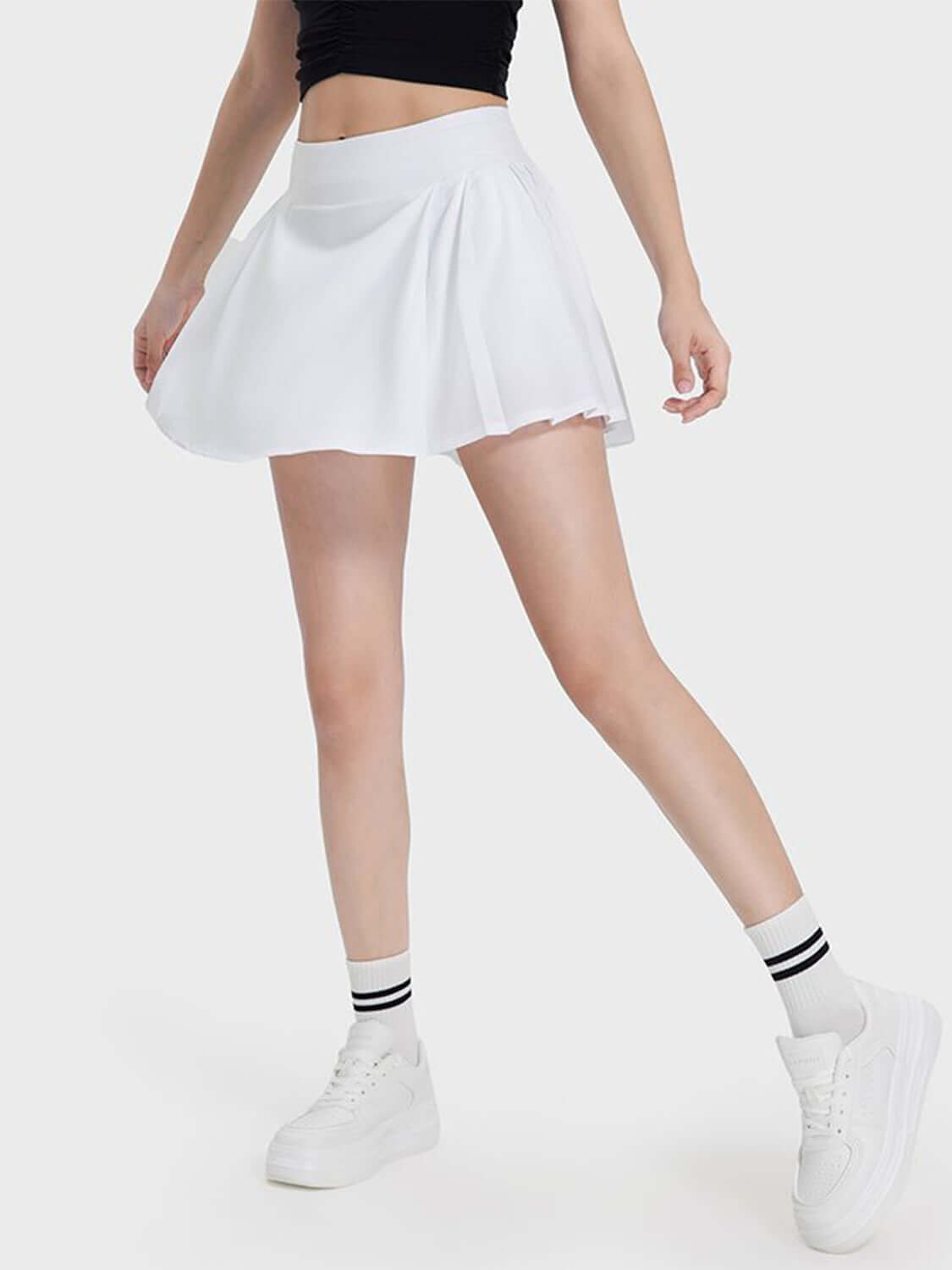 Active woman in a white pleated detail skirt, showcasing stylish comfort and flexibility for any activity.