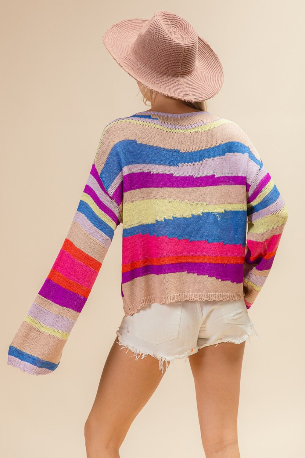 Woman wearing BiBi Multi Color Geometric Stripe Sweater and hat, showcasing vibrant stripes and modern design. Perfect for cooler days.