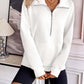 Woman wearing Ivy Lane Half Zip Raglan Sleeve Sweatshirt in white, styled with black shorts in a modern room setting