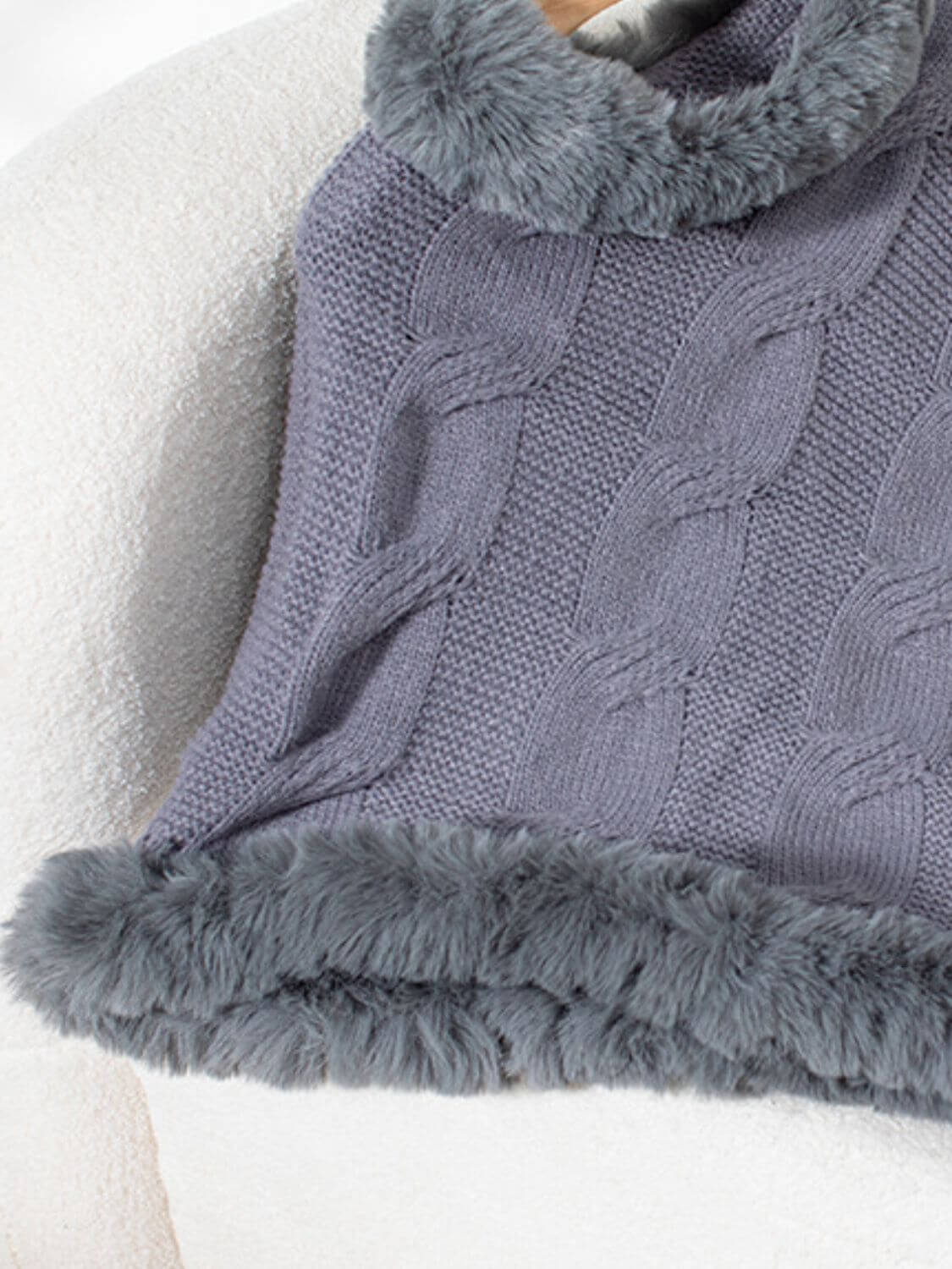 Cozy gray cable-knit poncho with fuzzy hem, perfect for stylish warmth on chilly days.