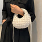 Woman holding a small quilted puffy crossbody bag with removable strap, perfect for versatile styling and chic fashion.