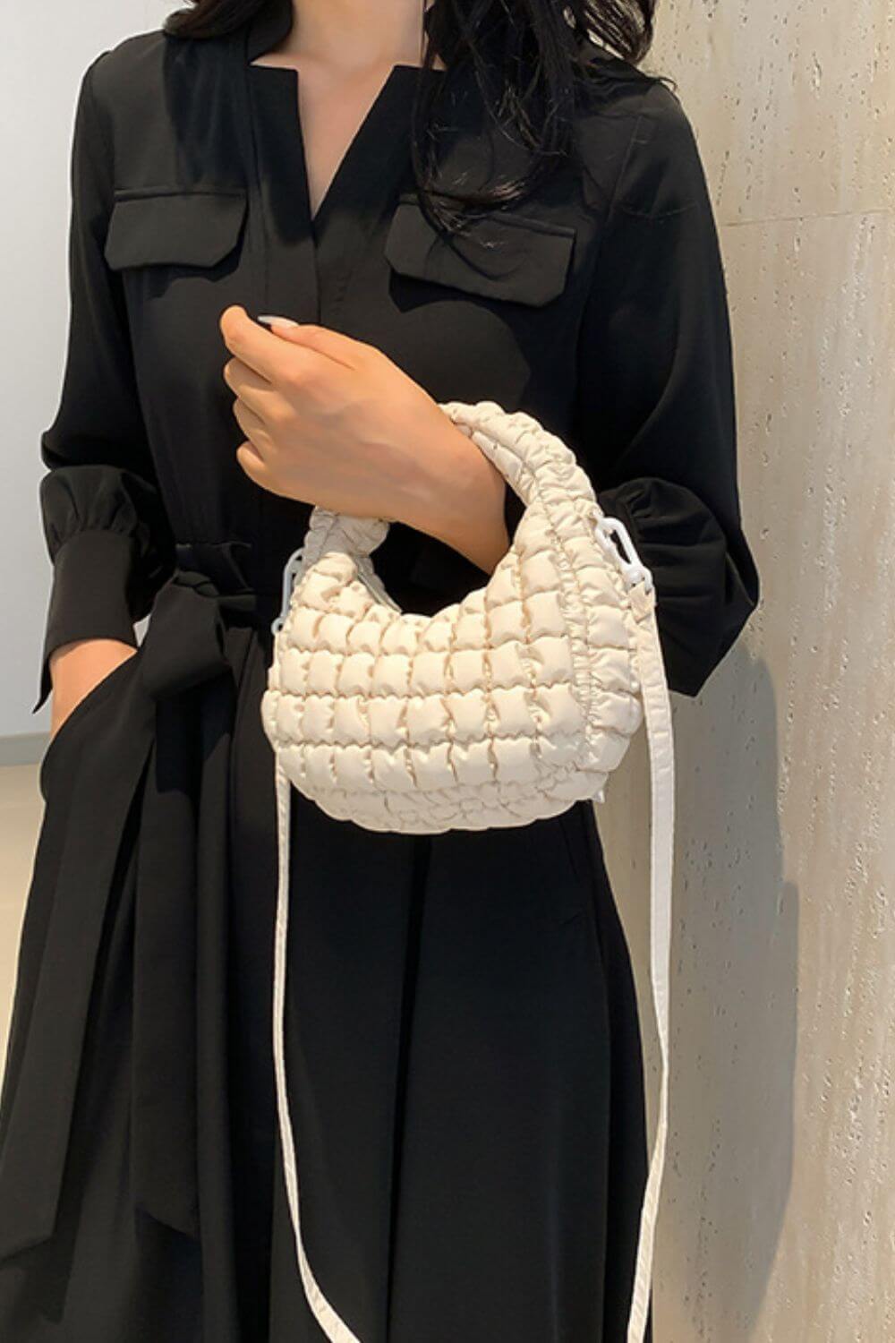 Woman holding a small quilted puffy crossbody bag with removable strap, perfect for versatile styling and chic fashion.