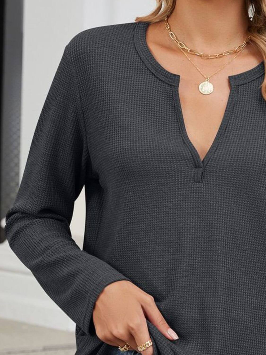 Woman wearing Bella Road waffle-knit notched long sleeve t-shirt in dark gray, accessorized with gold necklace.