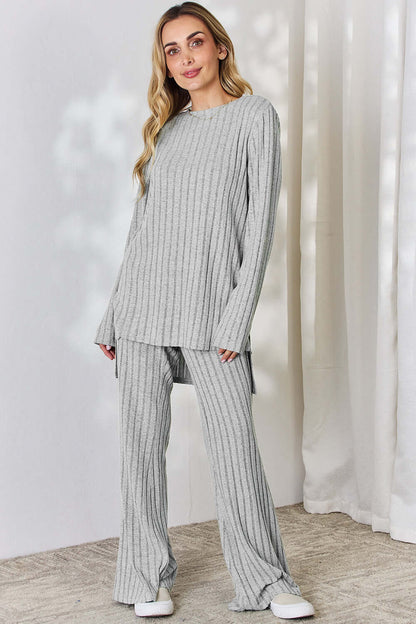 Woman wearing grey ribbed high-low top and wide leg pants set, slightly stretchy, two-piece outfit made of 96% polyester and 4% elastane.