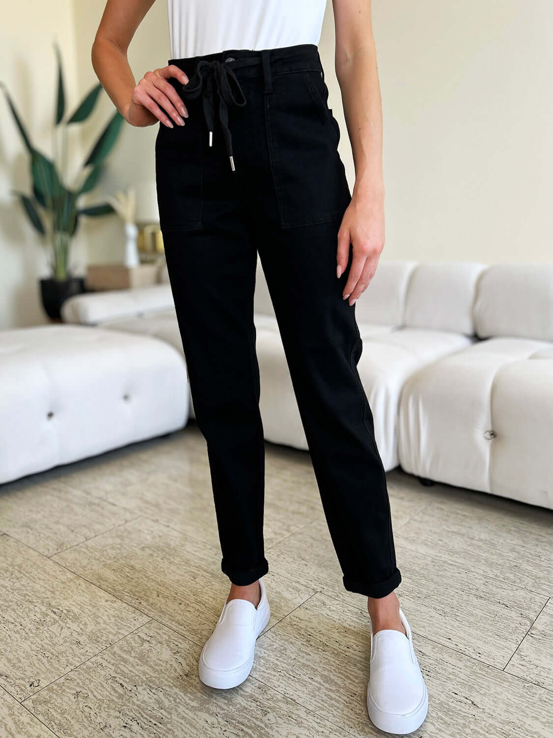 Woman wearing black high waist double roll cuff jeans by Judy Blue, featuring a trendy casual style with a drawstring waistband