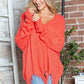 Woman wearing Bella Road Frayed Hem Dropped Shoulder Sweater in orange, adding playful style to a casual outfit.