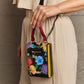 Woman holding Nicole Lee USA small crossbody wallet with floral pattern and adjustable strap.