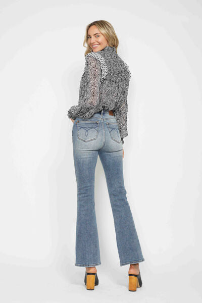 Woman wearing Judy Blue bootcut jeans with tummy control and embroidered pockets, styled with a trendy blouse.