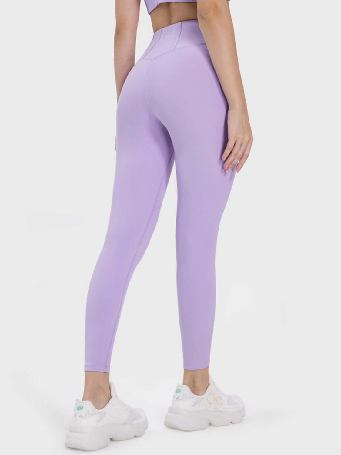 Stylish model showcasing Millennia Pocketed High Waist Active Leggings in lavender, perfect for workouts with functional pockets.