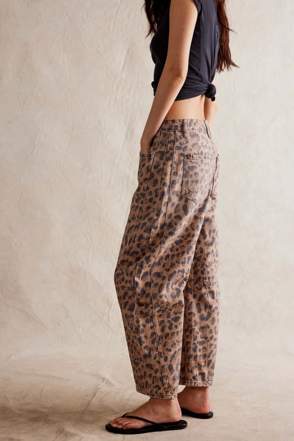 Leopard print wide leg jeans with pockets, modeled with a knotted black top and flip-flops.