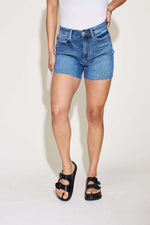 Woman wearing High Waist Slim Denim Shorts by Judy Blue Jeans with black sandals