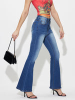 Woman wearing mid-rise waist bootcut jeans with no stretch, pocketed and buttoned, in blue, paired with black heels and a red crop top.