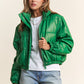 Chic green faux leather crop puff jacket with turtleneck, snap buttons, zipper closure, and drawstring hem; perfect for fall style.