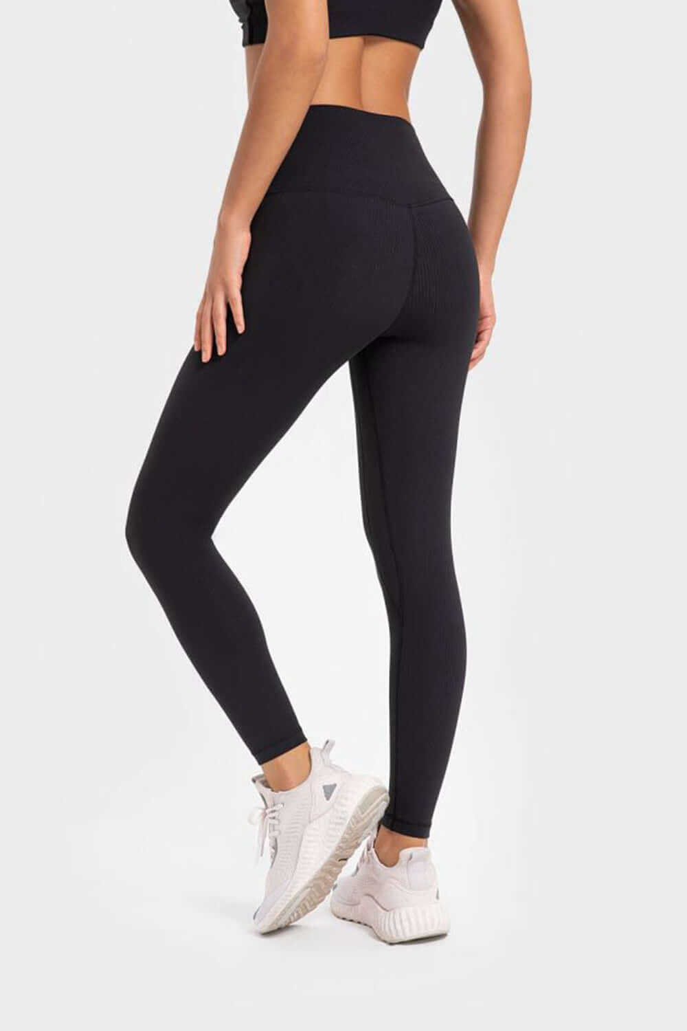 Woman in black Millennia High Stretchy Yoga Leggings showcasing a wide waistband, perfect for comfort and flexibility during workouts.