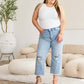 Woman wearing Tummy Control High Waist Raw Hem Distressed Jeans by RFM Jeans in a stylish living room.