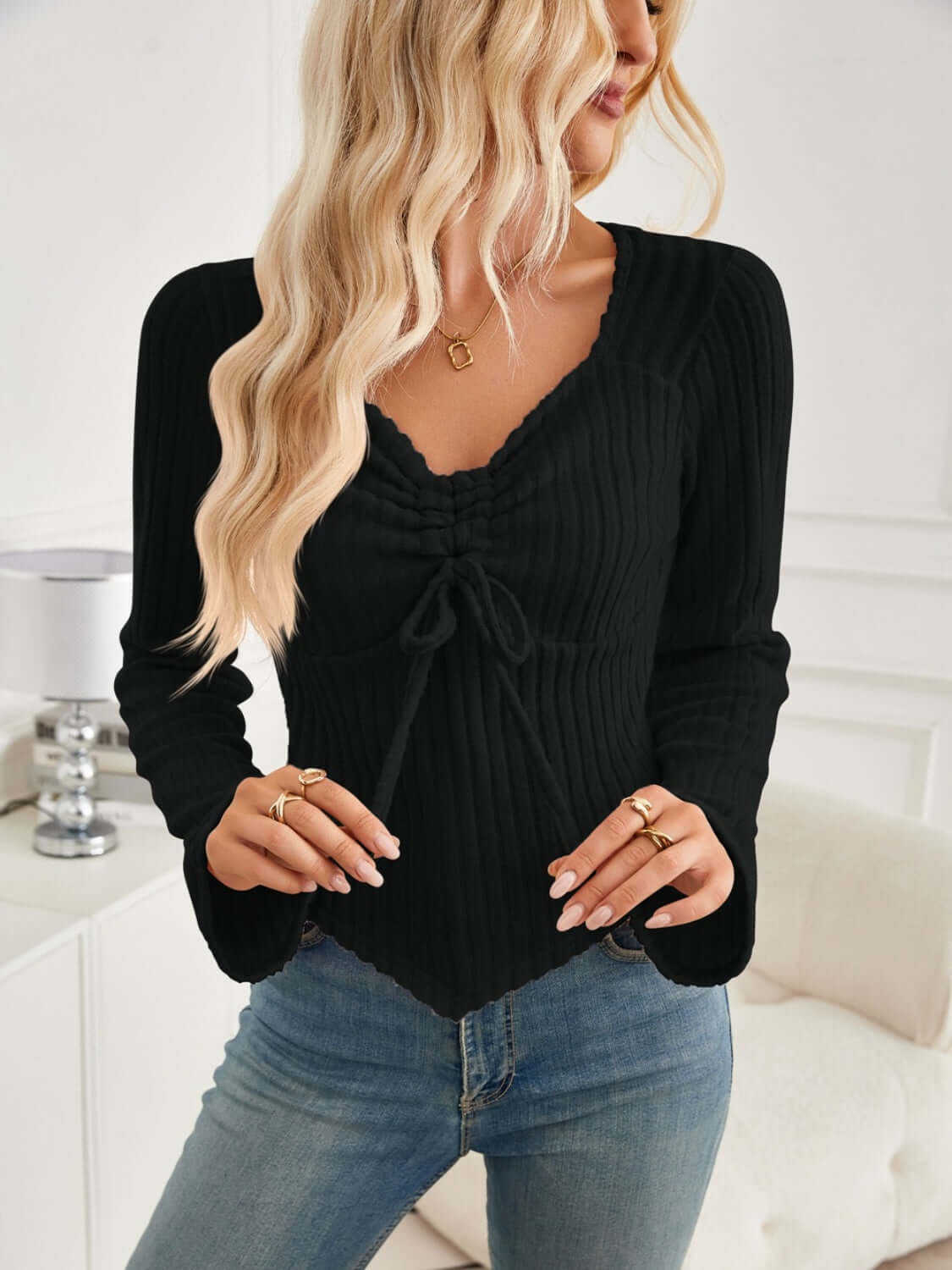 Woman wearing Bella Road Ribbed Drawstring Long Sleeve T-Shirt in black with slightly stretchy material, paired with denim jeans.