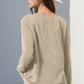 Woman wearing beige knit long sleeve sweater with thumbholes, paired with white hat and distressed shorts.