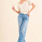 Woman wearing Back Waist Tie Cropped Blouse paired with high-waisted blue jeans and white ankle boots.