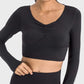 Model wearing the Millennia Ruched Cropped Long Sleeve Sports Top in black, showcasing its stylish design and fitted silhouette.