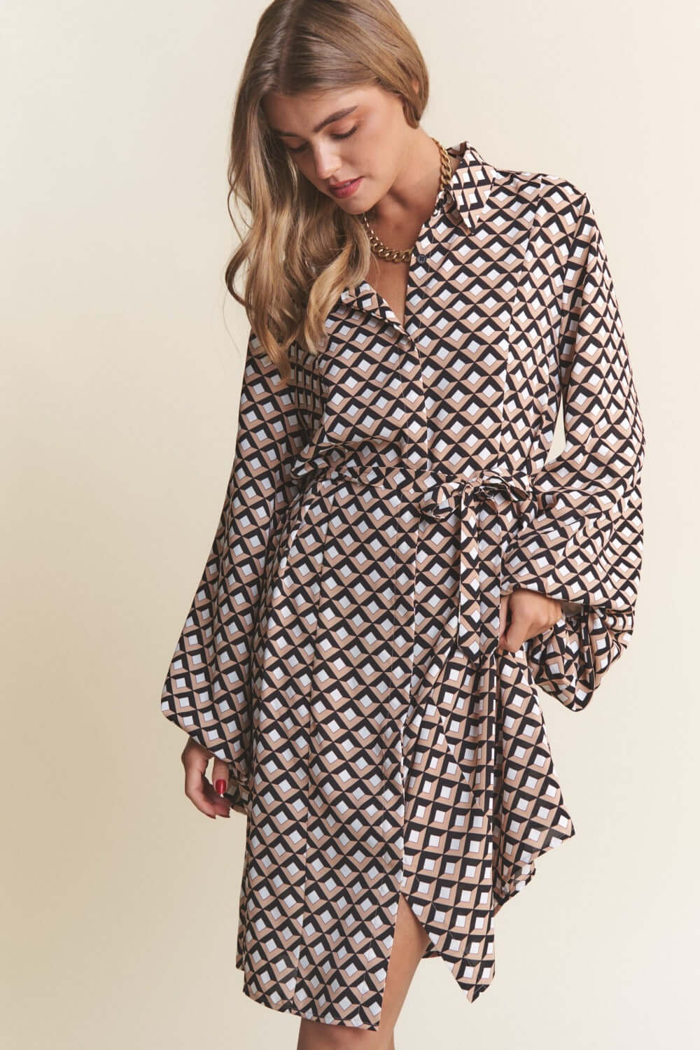 Woman wearing J.NNA geometric balloon sleeve midi dress with waist tie and trendy print.