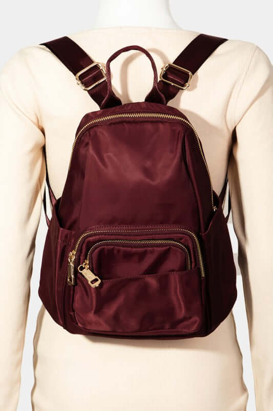 Burgundy multi pocket nylon backpack bag showcasing stylish design and practical storage on a mannequin.