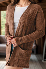 Woman wearing a textured open front cover up with pockets in brown, paired with a white top.