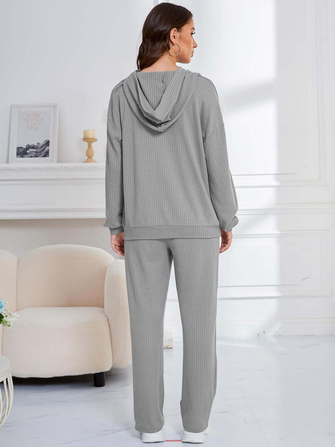 Woman wearing gray Bella Road Dropped Shoulder Hoodie and Pants Set, showcasing relaxed fit and cozy elegance for lounging or errands.