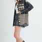 Trendy woman wearing Aem+Co plaid button-up shirt with curved hem, styled with denim shorts and stylish boots.