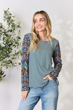 Woman wearing a striped round neck geometric long sleeve t-shirt with jeans, featuring a stylish and eye-catching design.