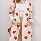 Woman wearing Bella Road Heart Open Front Long Sleeve Cardigan with red heart patterns and pockets. Stylish and cozy wardrobe essential.