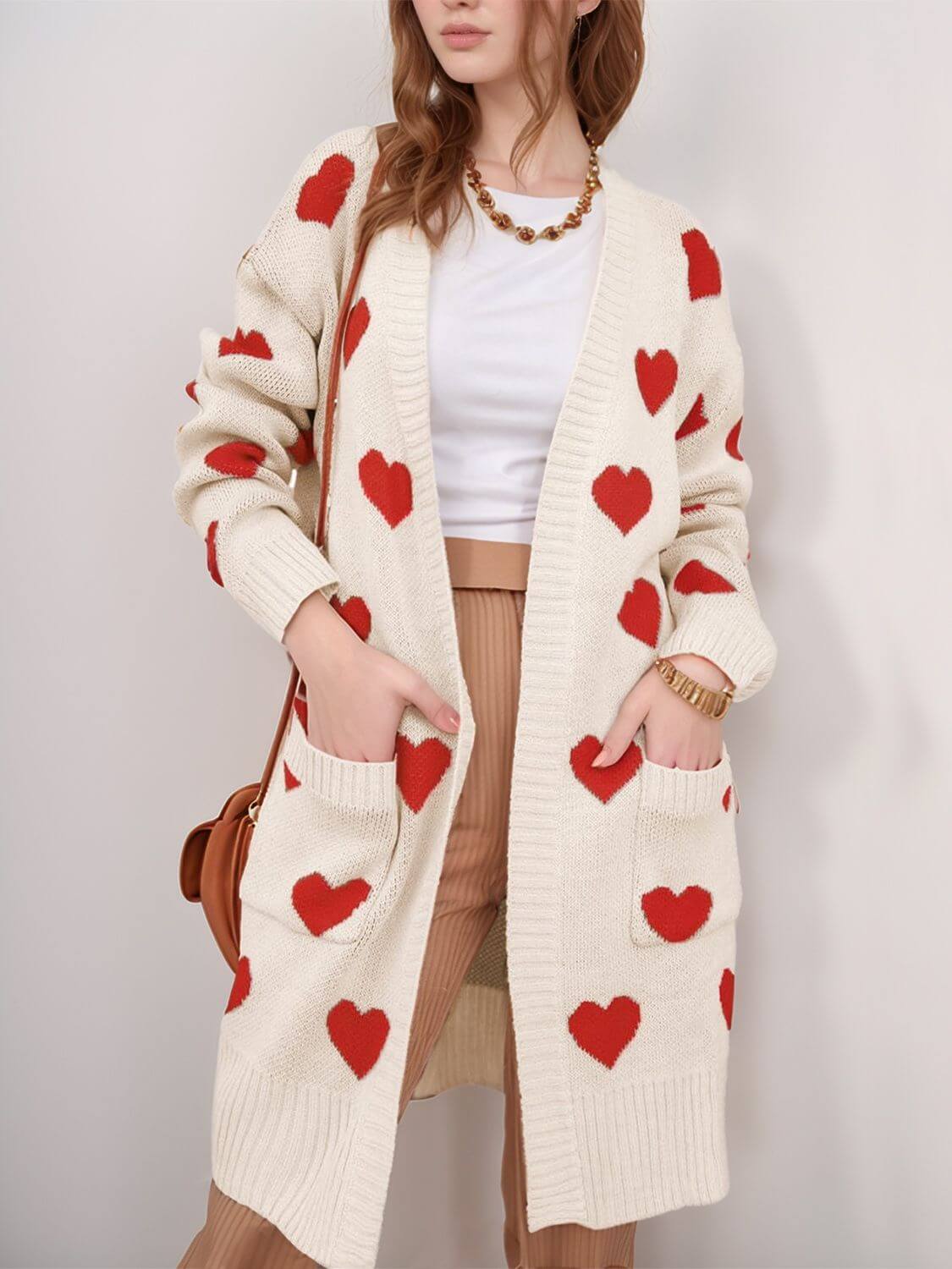 Woman wearing Bella Road Heart Open Front Long Sleeve Cardigan with red heart patterns and pockets. Stylish and cozy wardrobe essential.