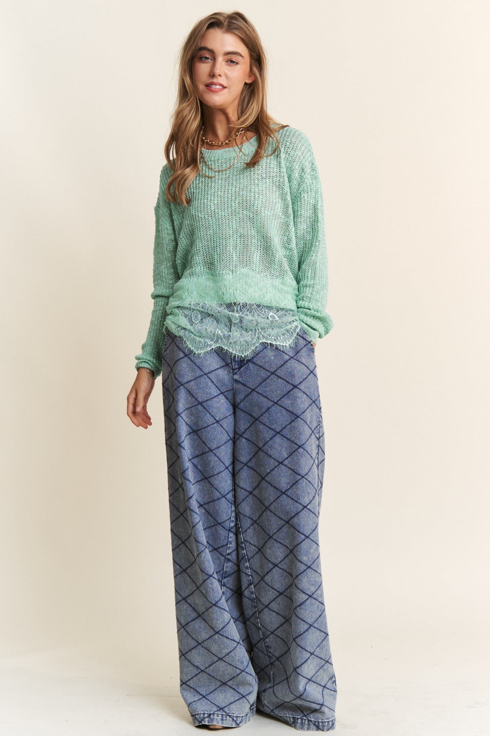 Woman wearing J.NNA lace detail long sleeve knit top in green with wide-legged patterned pants.