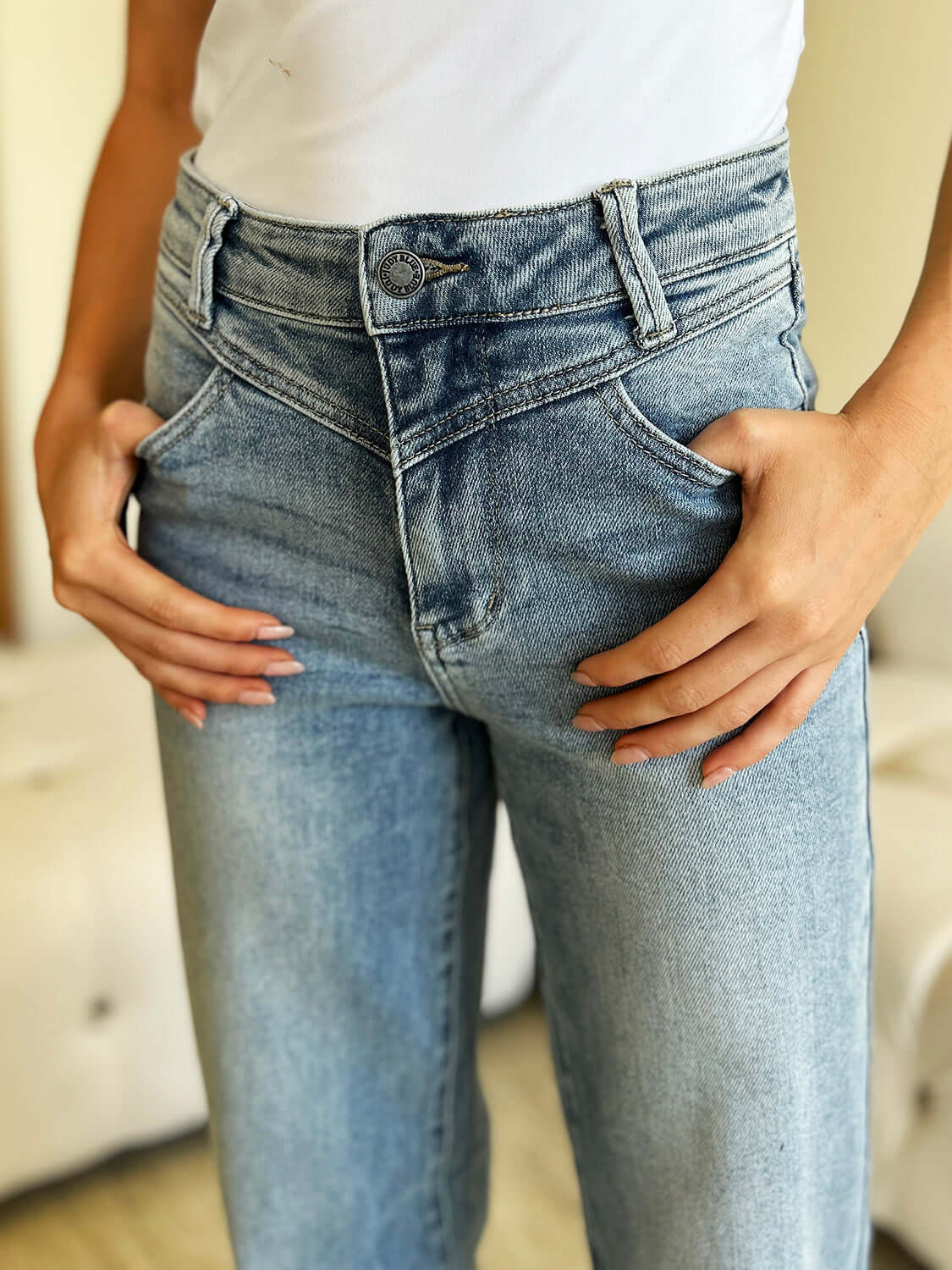 Close-up of person wearing High Waist Wide Leg Judy Blue Jeans showing front pockets and button fastening.