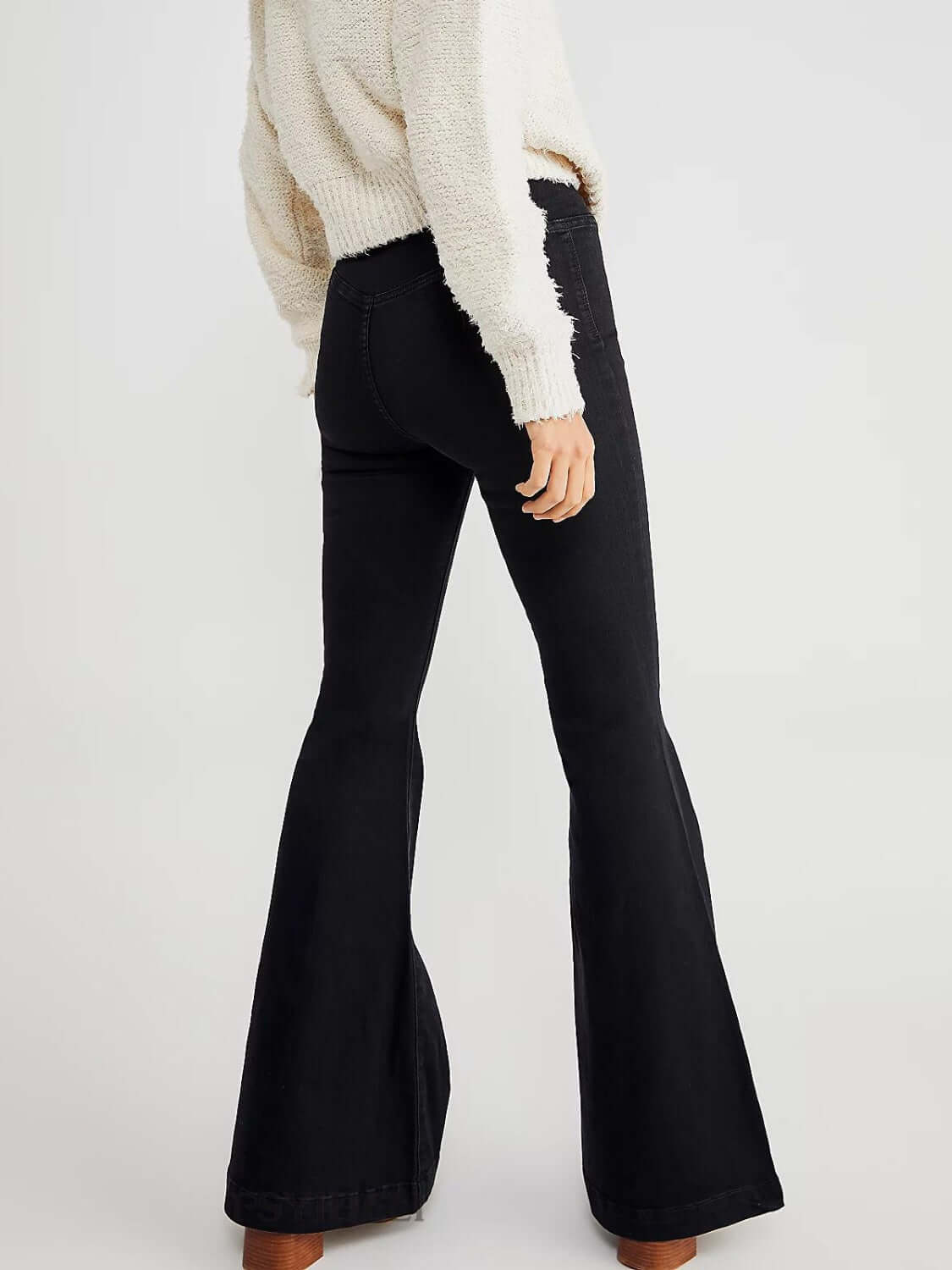 Woman wearing Asymmetric Waist Flare Jeans in black, showcasing the unique asymmetric waistline and flare leg design.