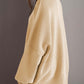 Woman wearing a cozy double take side slit round neck long sleeve sweater in beige, showcasing back side split detail.