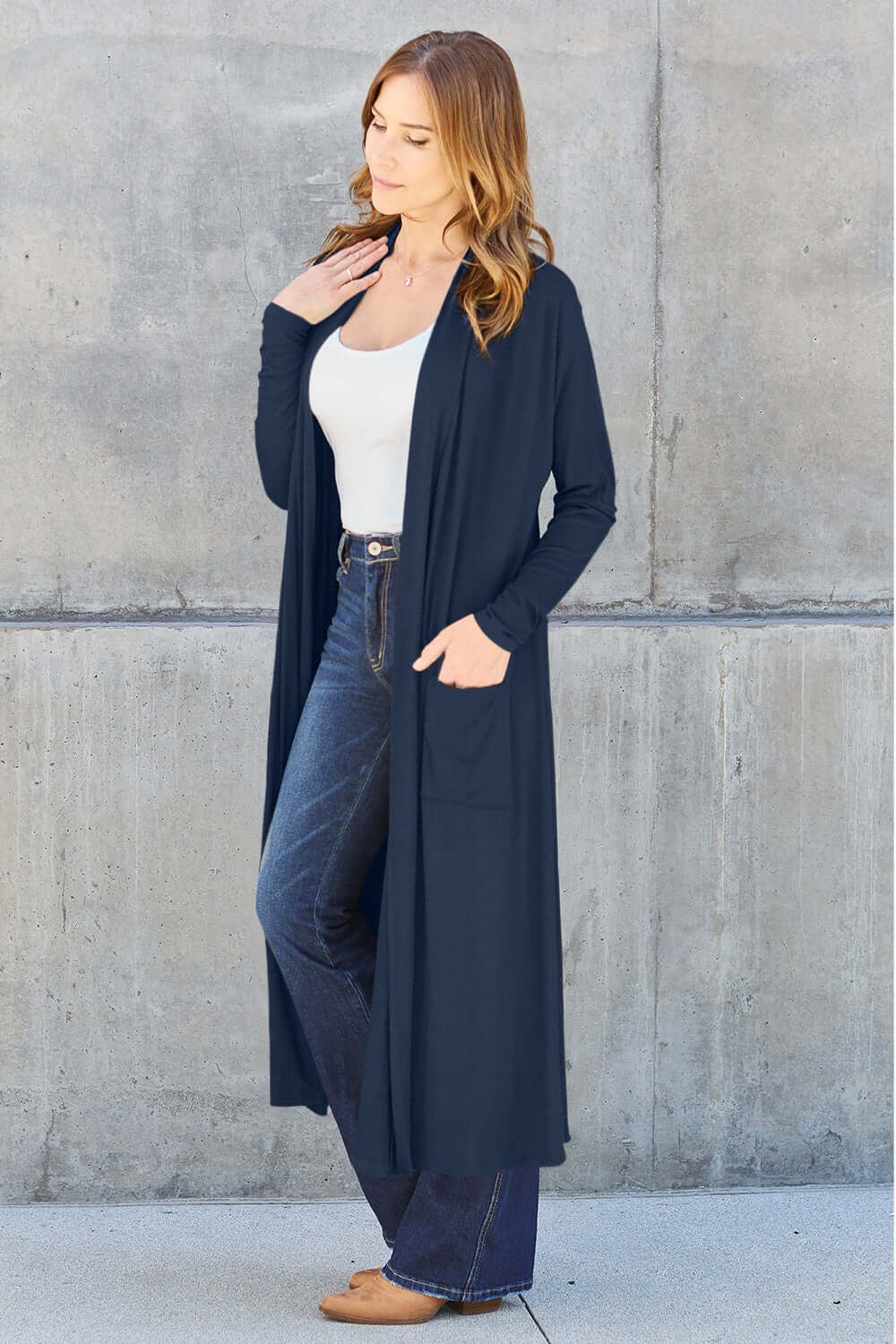 Woman wearing open front long sleeve cover up with pockets in navy blue over casual white top and jeans