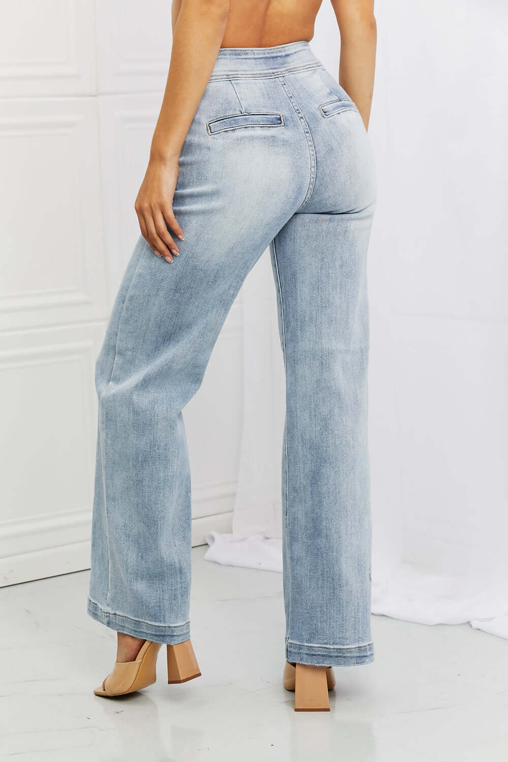 Woman wearing Luisa Wide Flare Jeans by Risen Jeans, showcasing high waist and wide flare design with functional back pockets.