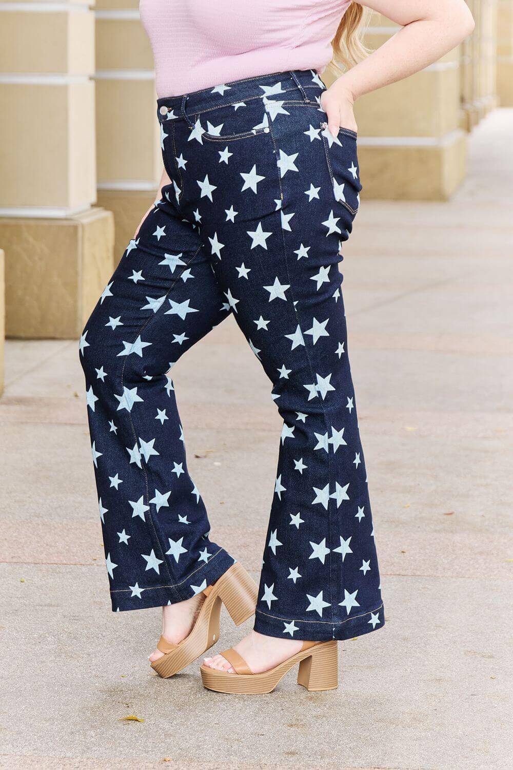 Woman wearing Janelle Full Size High Waist Star Print Flare Judy Blue Jeans with dark wash and star design.