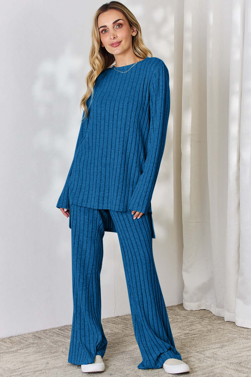 Woman wearing a blue ribbed high-low top and wide leg pants set made of slightly stretchy polyester-elastane blend, perfect for casual wear.