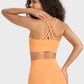 Woman in orange crisscross active tank showcasing stylish back design, ideal for workouts and comfort.