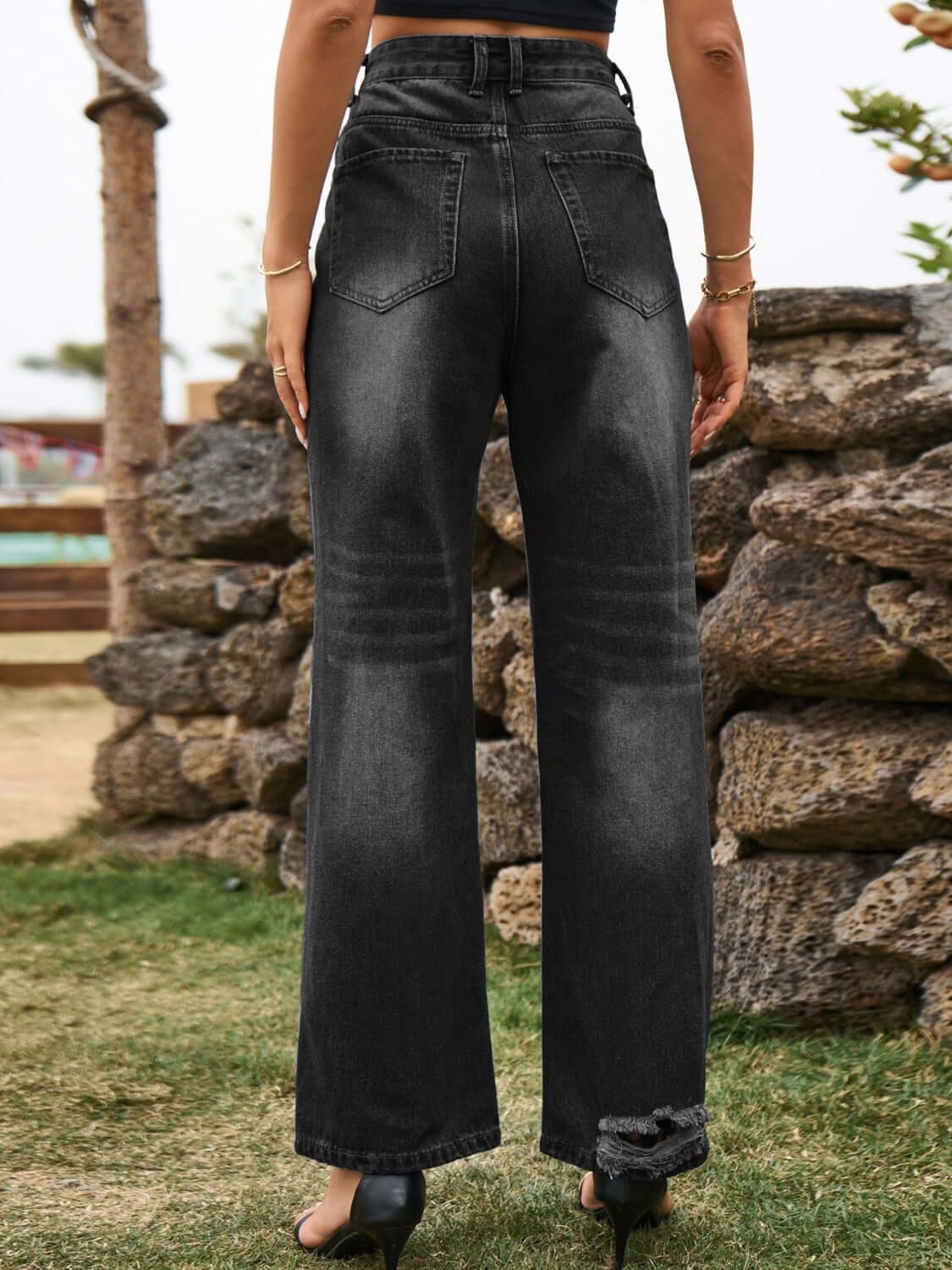 Black distressed jeans with stylish pockets, high waist, and relaxed fit, perfect for an edgy look.