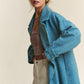 Woman wearing a blue J.NNA tweed double-breasted long sleeve coat, styled with a top and pants for a chic look.