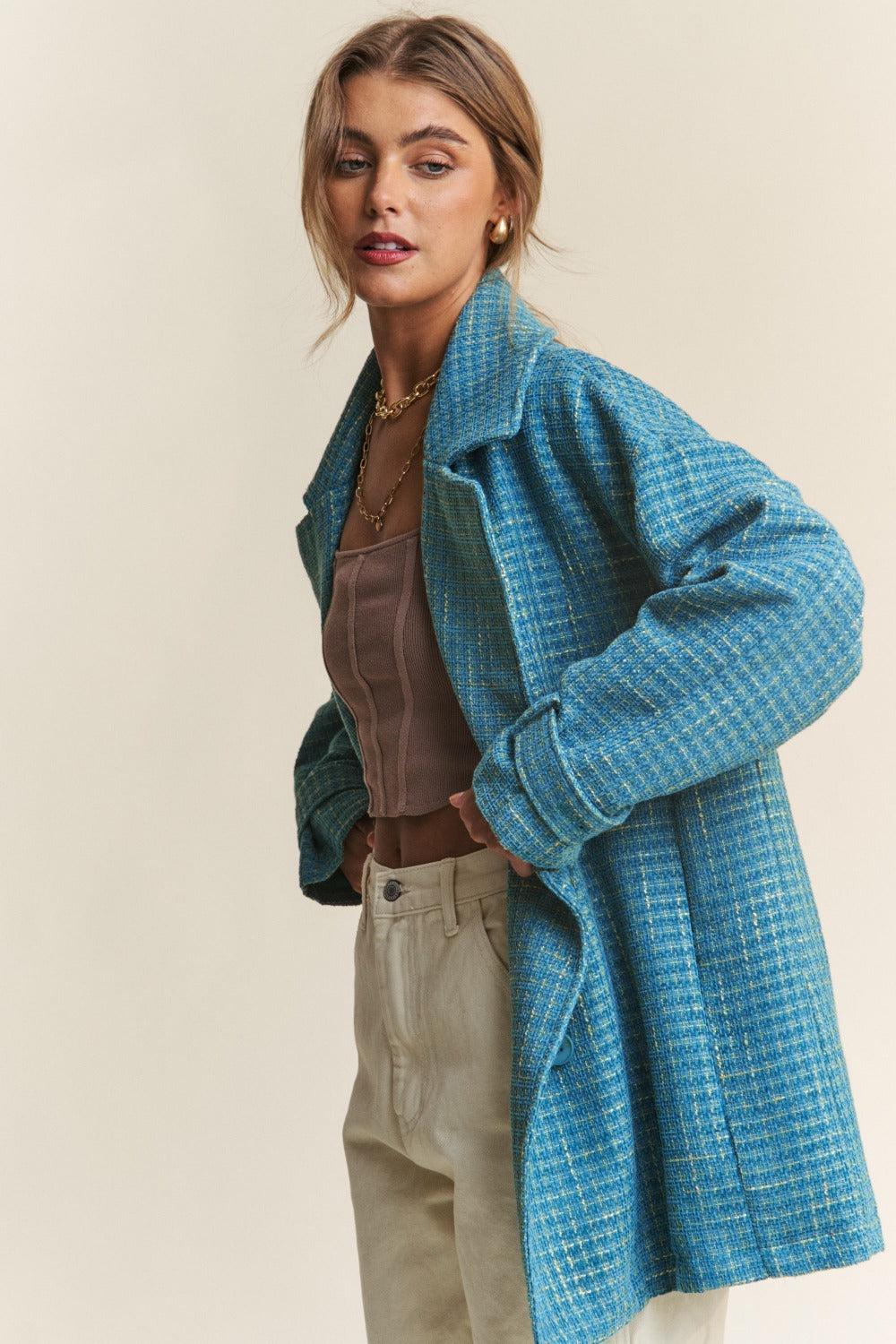 Woman wearing a blue J.NNA tweed double-breasted long sleeve coat, styled with a top and pants for a chic look.