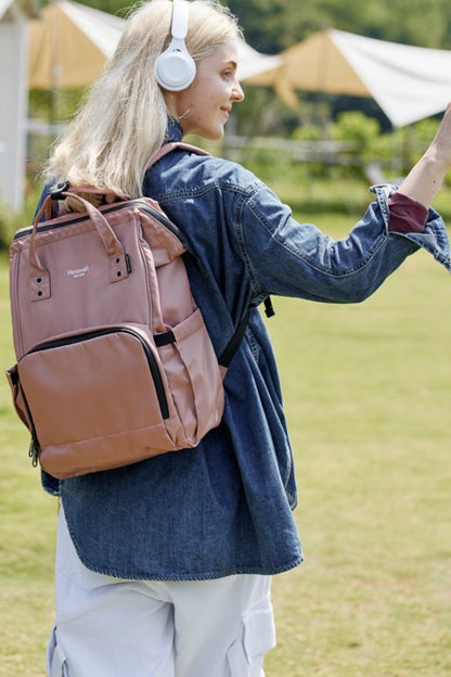 Woman wearing Himawari waterproof anti-theft nylon backpack outdoors, paired with white headphones and denim jacket.