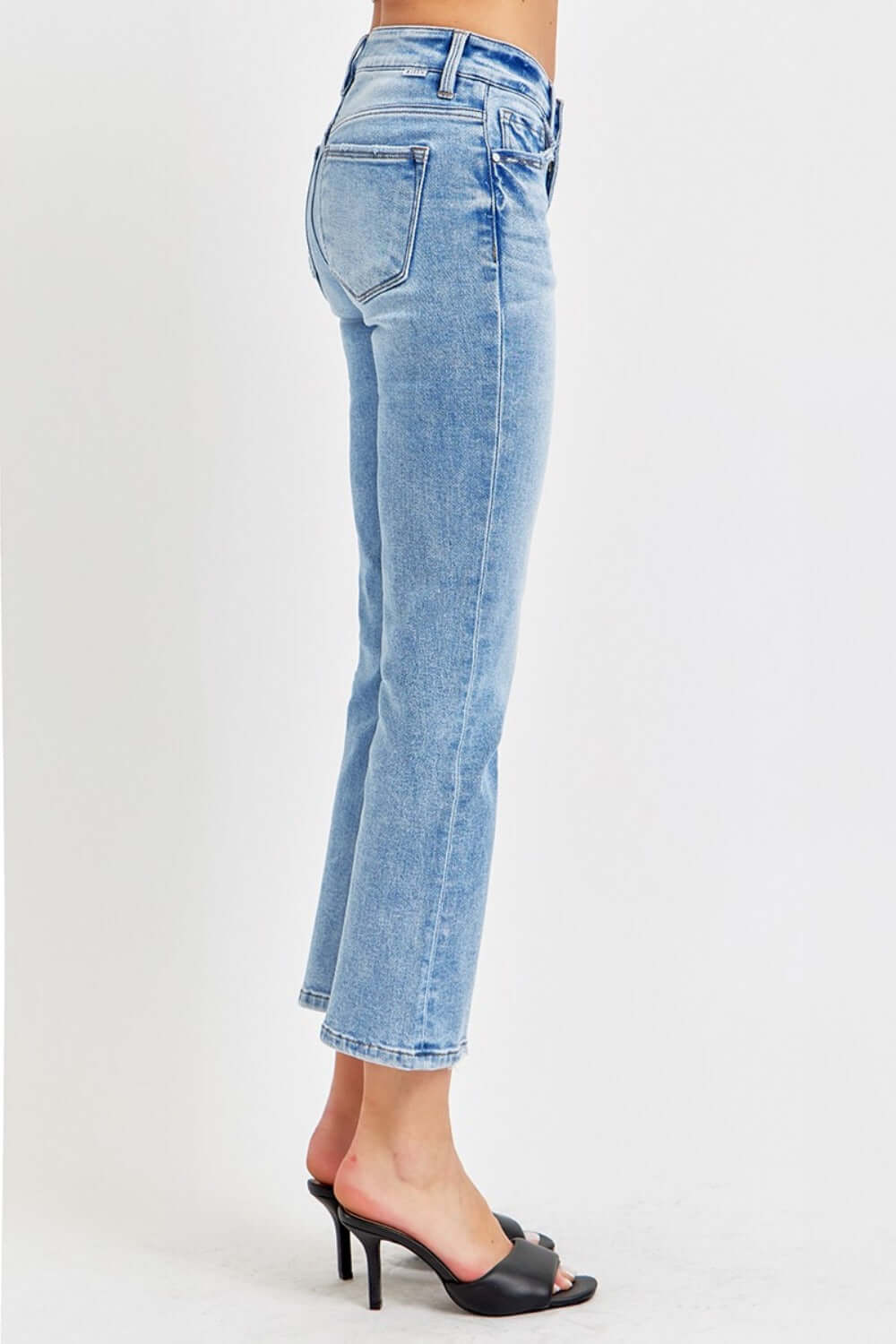 Woman wearing RISEN full size low rise crop slim straight jeans with raw hem and black heels.